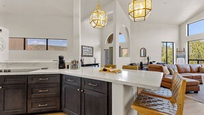 A modern kitchen with dark cabinetry, a marble island, and pendant lighting.