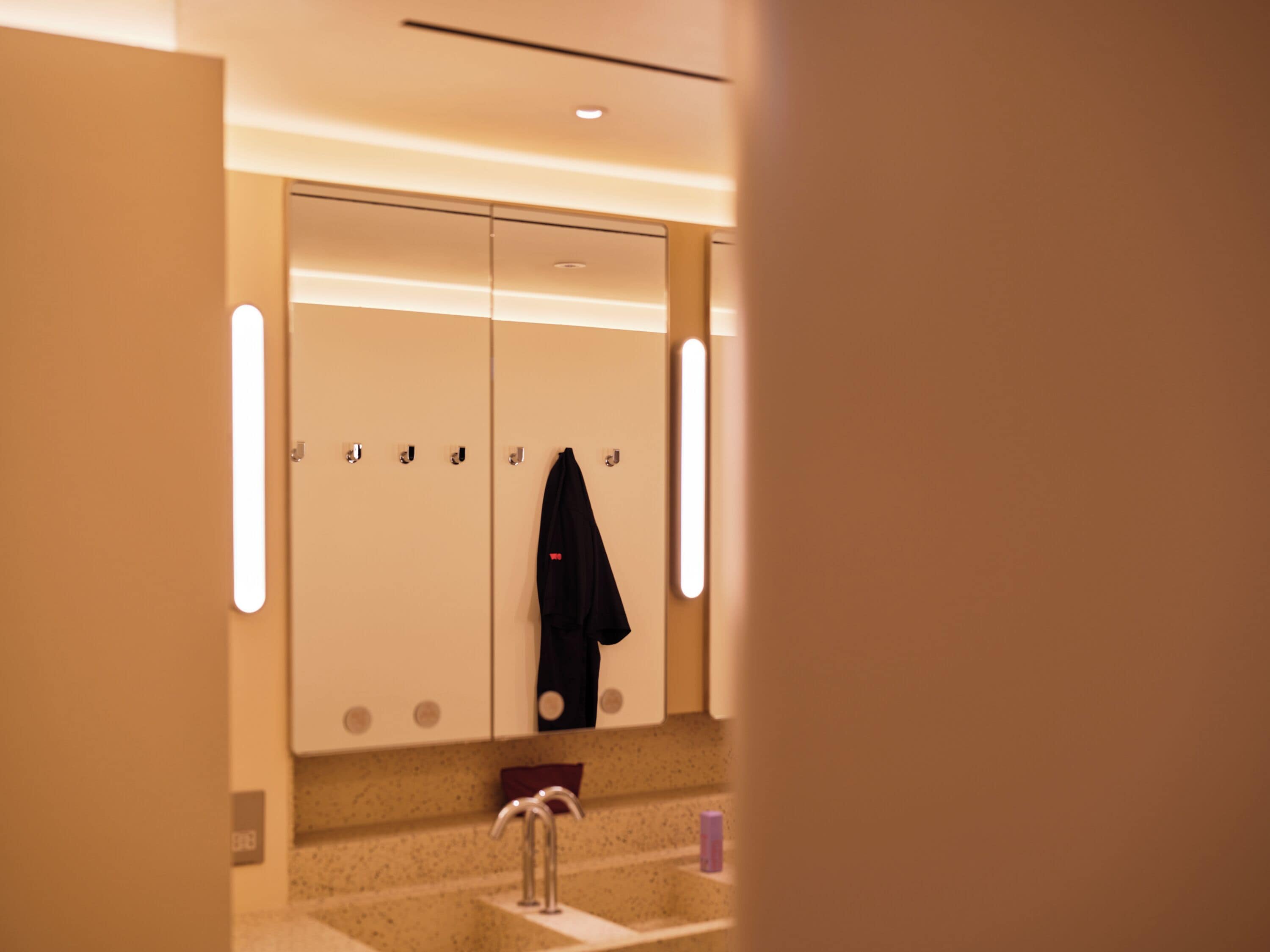 Una camera d'albergo con una porta a doppio battente, un lavandino e uno specchio.