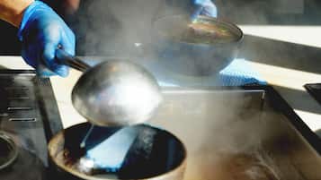 A person cooking with steam rising from a pot, using a ladle.