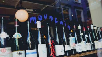 A row of wine bottles with labels, some with red ribbons, in a dimly lit setting.