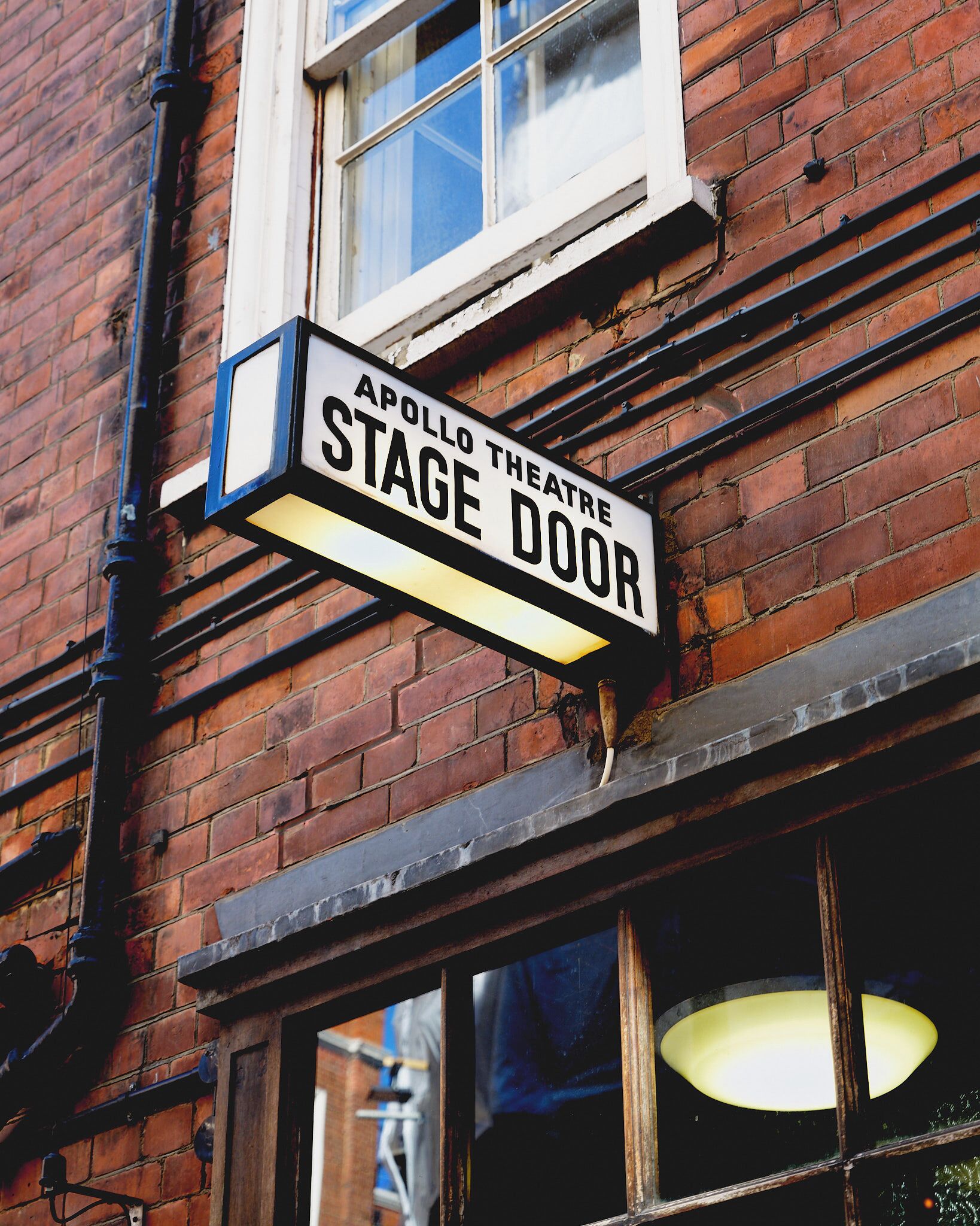 A sign for 'Apollo Theatre Stage Door' on a brick building.