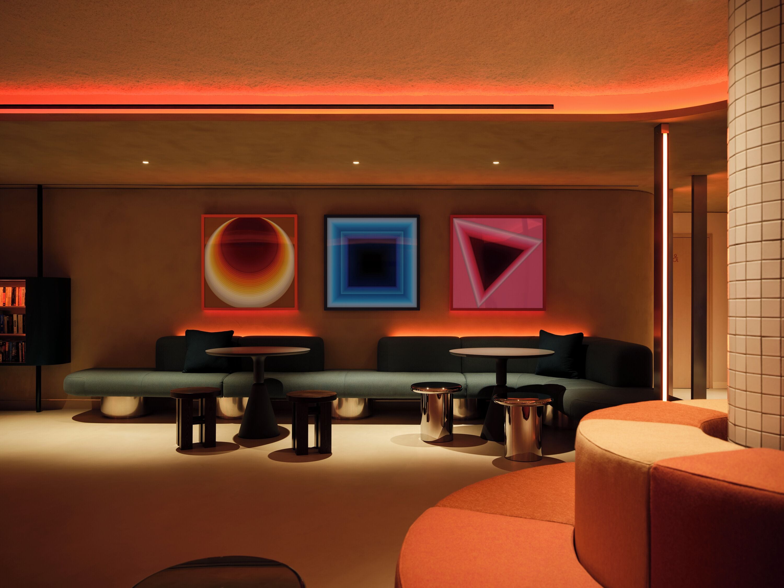A modern lounge area with a sofa, tables, and abstract wall art.