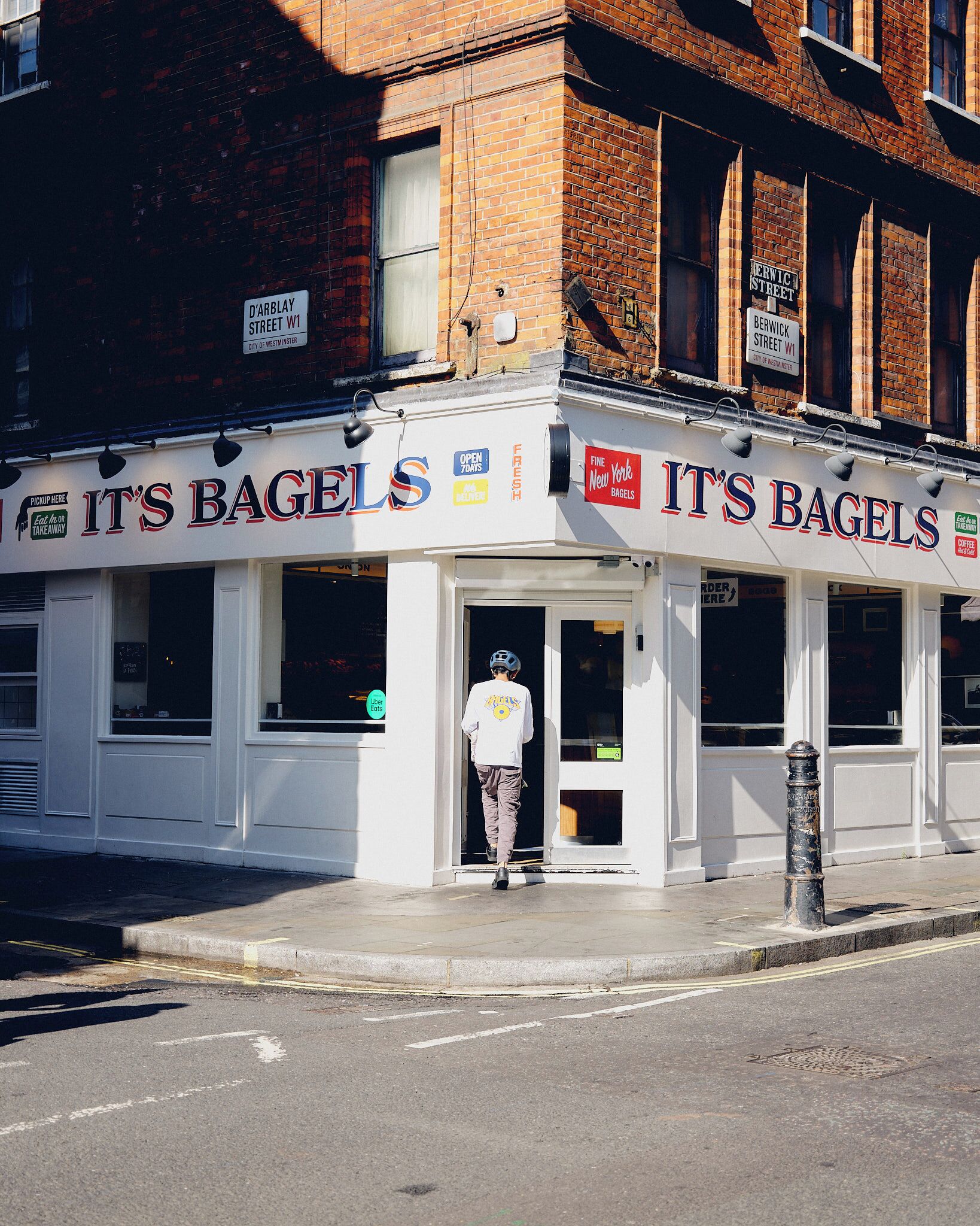 Une devanture de magasin avec une enseigne indiquant « ON VEND DES BAGELS » et une personne qui sort du bâtiment.