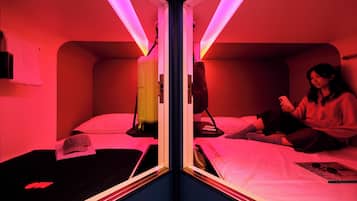 A mirrored room with two beds, a heater, and a person using a smartphone.