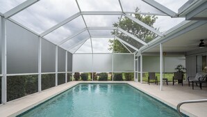 Ein überdachter Pool mit Glasdach, umgeben von einer Terrasse mit Stühlen und Blick ins Freie.