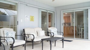 Ein überdachter Patio-Bereich mit einer Sofagarnitur, einem Tisch und einem Deckenventilator.