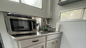 A compact kitchen with a built-in microwave, a stainless steel sink, and white cabinetry.