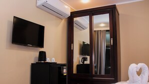 Habitación de hotel con televisión de pantalla plana, minibar, armario y cama con toalla en forma de corazón.