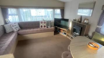 Un espace de vie compact comprenant un canapé, un téléviseur, une cheminée et une table à manger.