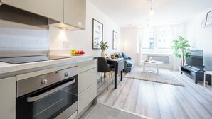 Una cucina moderna con forno a incasso, una zona pranzo con tavolo e sedie e un soggiorno con divano e televisore.
