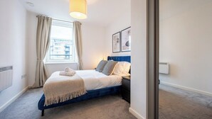 Una camera da letto con un letto, una finestra con tende, un termosifone e quadri appesi al muro.
