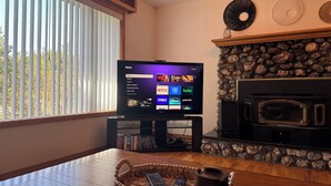 A living room with a television on a stand, a fireplace, and a stone wall.