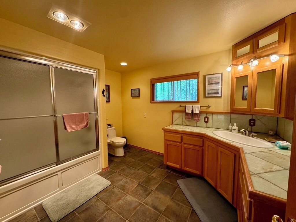 Une petite salle de bain comprenant une douche, des toilettes et un meuble-lavabo avec un évier.