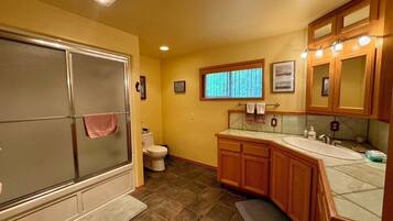 Une petite salle de bain comprenant une douche, des toilettes et un meuble-lavabo avec un évier.