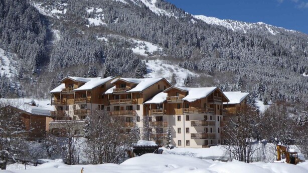 A multi-story lodge with balconies, set against a snowy mountain backdrop. - 1st floor, swimming pool, balcony, parking, tv, ski locker, 36m², Pralognan-la-Vanoise (Pralognan-la-Vanoise)