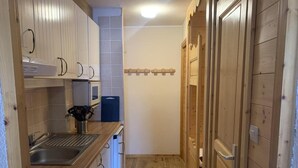 Een kleine keuken met houten kastjes, een spoelbak en een magnetron.