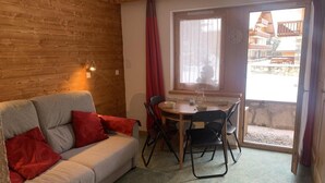 Een gezellige kamer met een bank, een eettafel en stoelen.