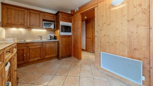 Una cucina con mobili in legno, un forno a microonde, un forno e un pavimento piastrellato.