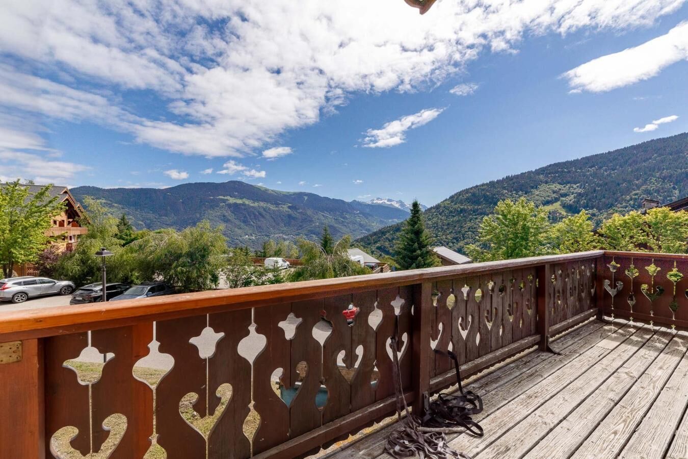 Una terraza de madera con vistas a montañas y un edificio de techo inclinado.