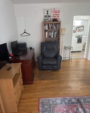 Un saló amb una cadira de cuir negre, mobles de fusta, una biblioteca i una catifa vermella.