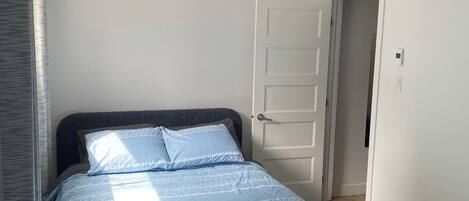 A bedroom with a bed, a door, and a light fixture.