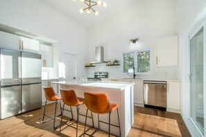 Een moderne keuken met een centraal eiland, roestvrijstalen apparatuur en een groot raam.