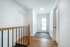 A hallway with a wooden staircase, white doors, and a ceiling light. - Grand Aylmer, SPA, Bord De l'eau (Beaulac-Garthby)