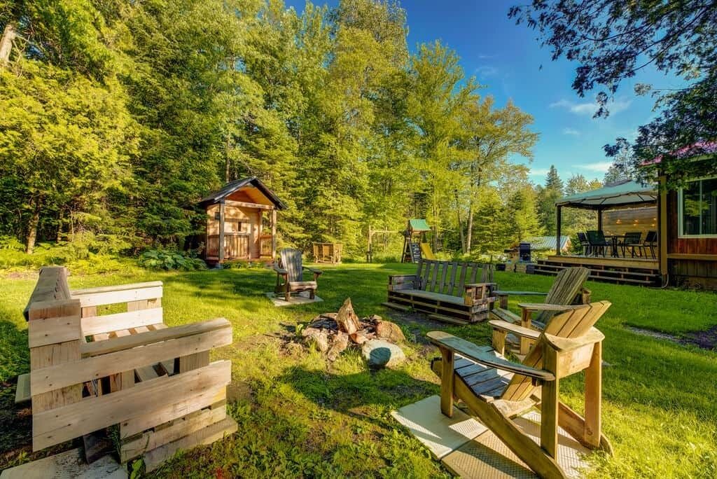 A rustic cabin with a deck, outdoor seating, and a fire pit.