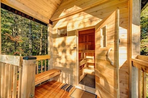 A wooden cabin with a porch, a door leading to an interior room, and a bench.
