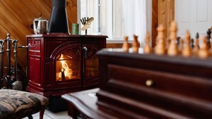 Um quarto aconchegante com uma lareira a lenha, um tabuleiro de xadrez e um banco de madeira.