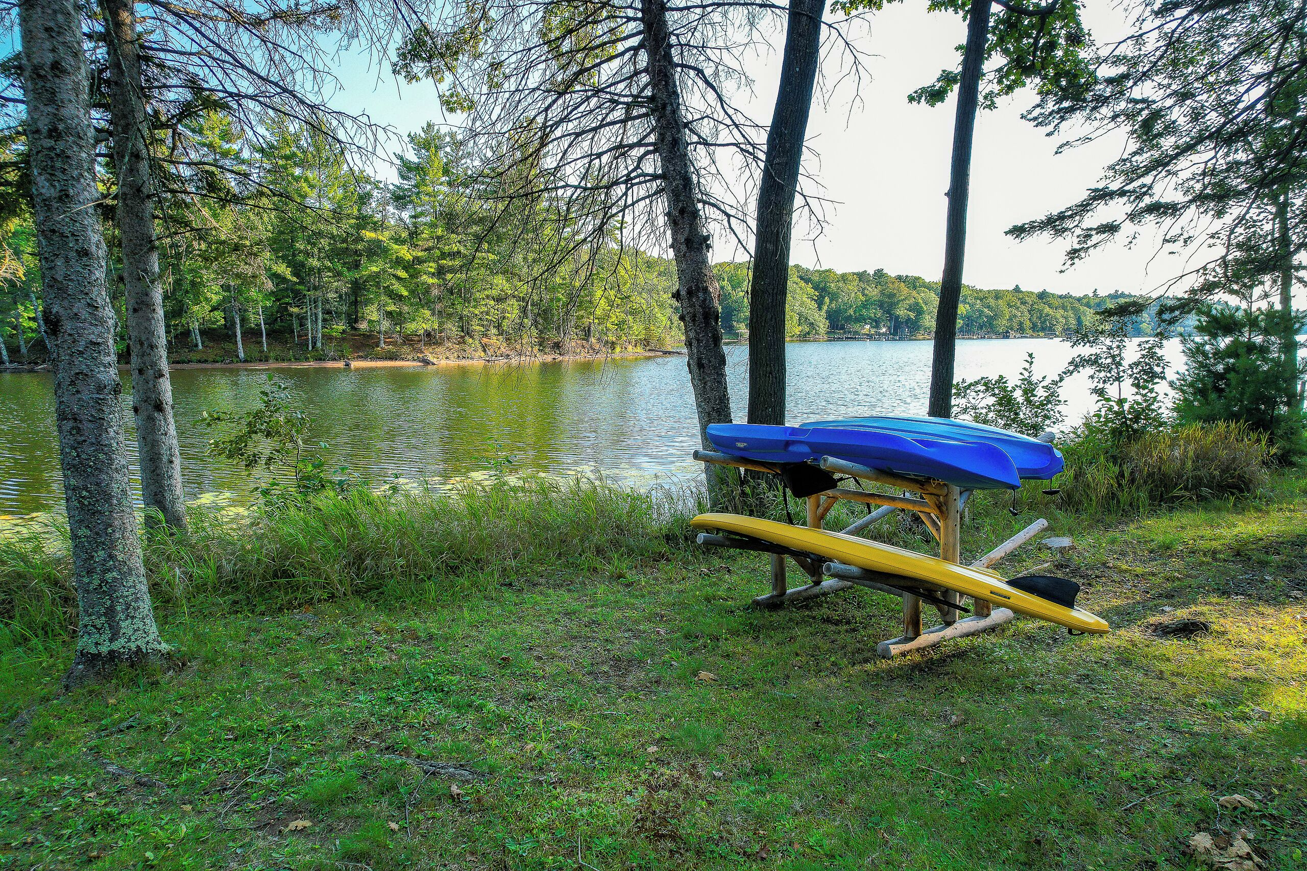 Un paisaje junto al lago con un canoa y un kayak apoyados en una estructura de madera.