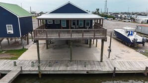 A waterfront property with a covered deck, a dock, and a boat.