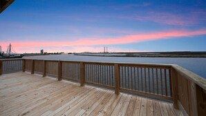 A wooden deck with a view of a river and distant structures.