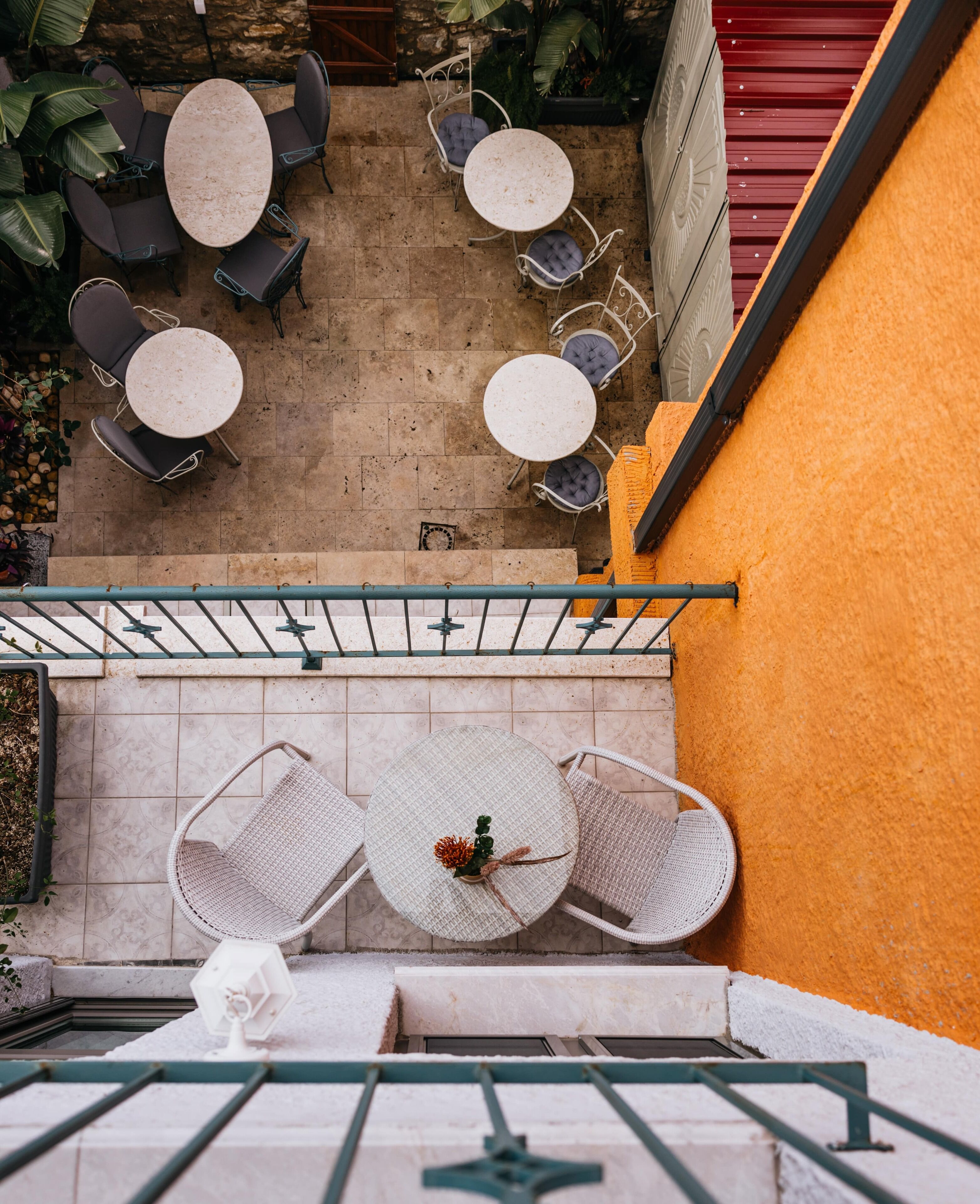 An outdoor patio with round tables and chairs, a staircase, and a yellow wall.