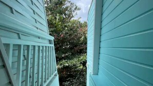 A narrow staircase leading to a covered outdoor area with a view of trees and shrubs. - LILI Apartment with swimming pool, 400m from the beach. (Les Trois-Îlets)