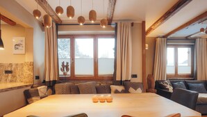Ein gemütlicher Essbereich mit einem großen Holztisch, gepolsterten Sitzgelegenheiten und Pendelleuchten.