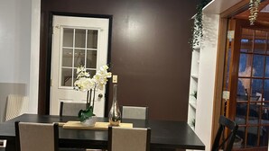 A dining area with a dark wooden table, four chairs, a vase with flowers, and a ceiling light fixture. - 4-bedroom home in Eagen,family friendly, centrally located with fenced backyard (Eagan)