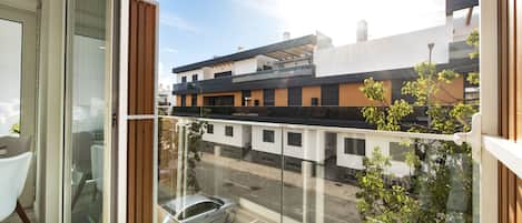 Un apartamento moderno con balcón, ventanas amplias y vista a la calle.
