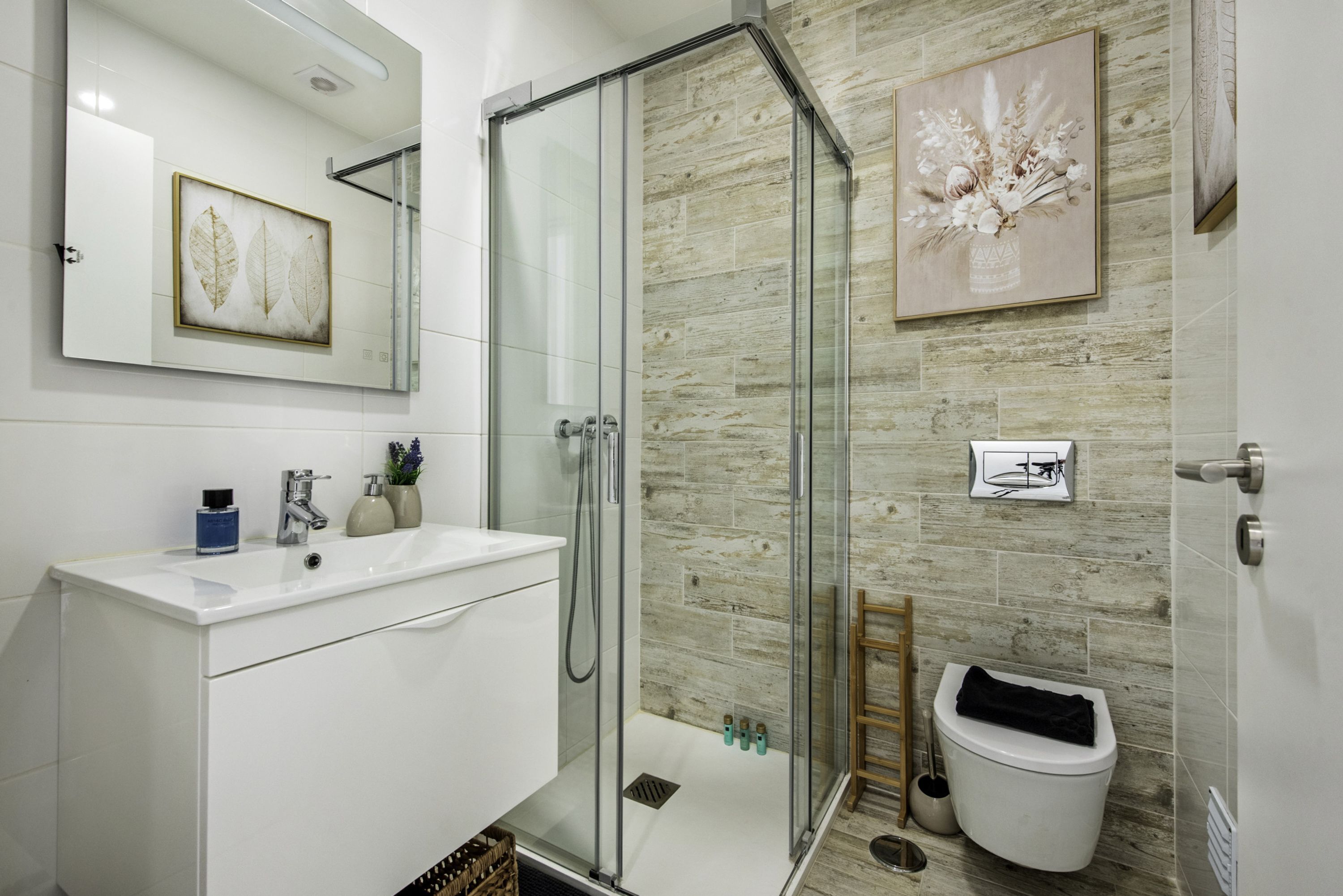Une salle de bain moderne avec une douche à parois de verre, un lavabo blanc et des toilettes.