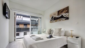 Et moderne soveværelse med en stor seng, et natbord, et maleri og en skydedør til en balkon.