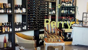 A wine cellar with numerous bottles, a wooden chair, and a table. - Newly Built, Modern Home Sleeps 10 on Houston Lake in beautiful Perry, GA! (Perry)