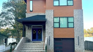 A modern two-story house with a brick facade, a front porch, and a garage. - Newly Built, Modern Home Sleeps 10 on Houston Lake in beautiful Perry, GA! (Perry)
