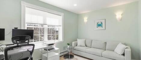 A modern office space with a desk, chair, and a white sofa.