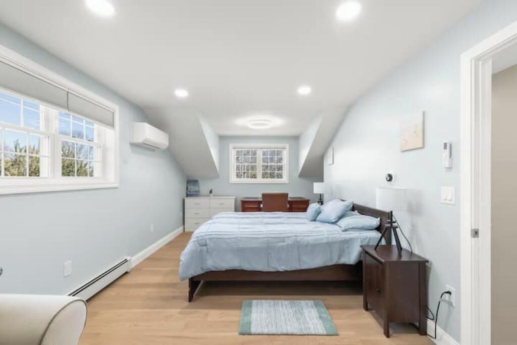 Un dormitorio con una cama grande, un escritorio, una silla y una ventana.