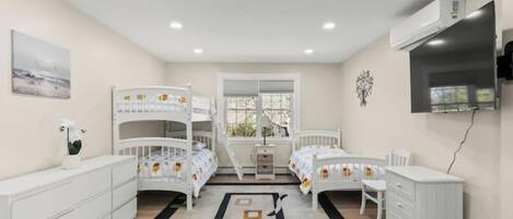 A child’s bedroom with bunk beds, a desk, and a TV.