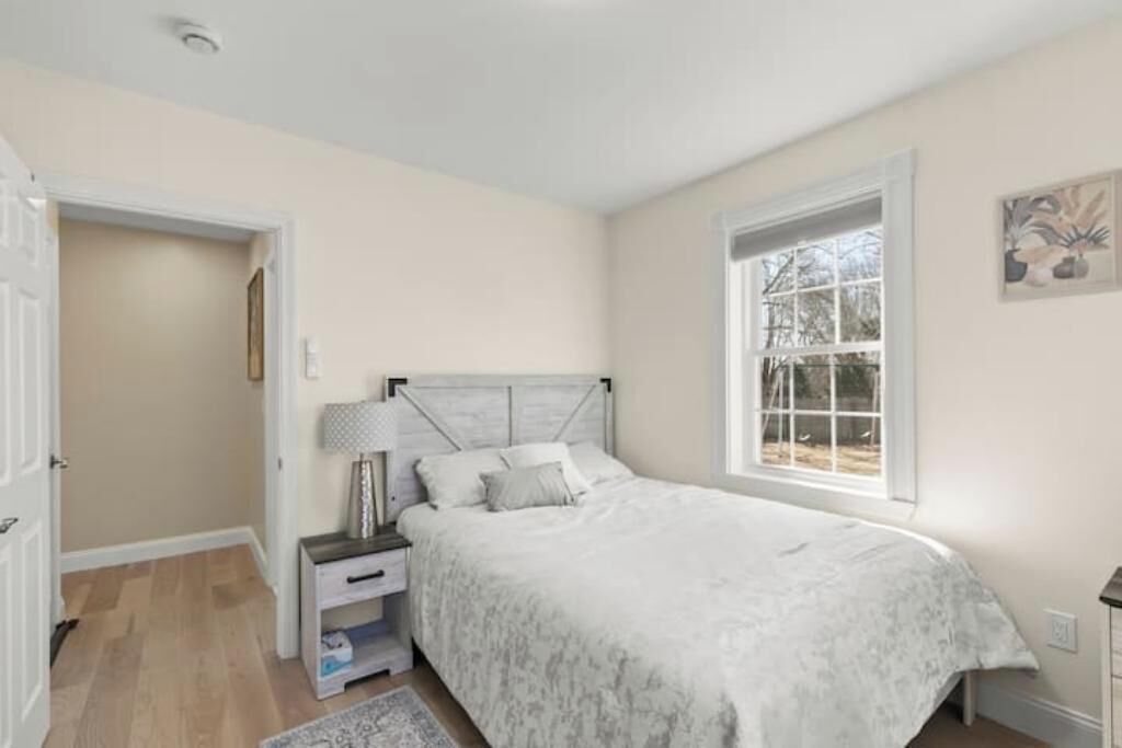 Een slaapkamer met een bed, nachtkastjes, een lamp, een raam en een deur.