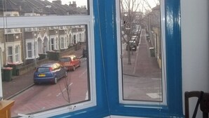 Ein Zimmer mit großem Fenster und Blick auf eine Wohnstraße mit Reihenhäusern.