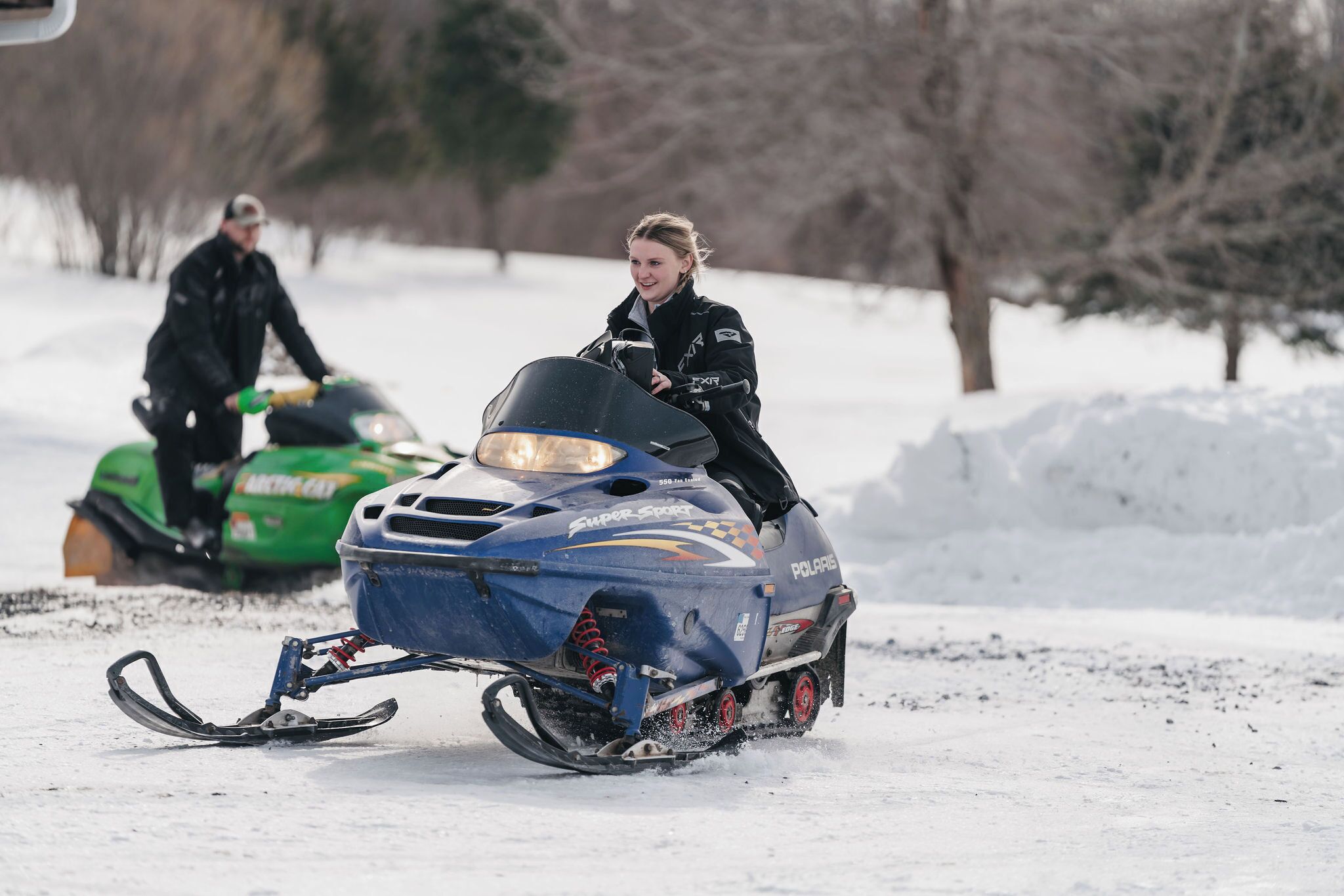 A person riding a snowmobile on a snowy surface.