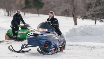 A person riding a snowmobile on a snowy surface.