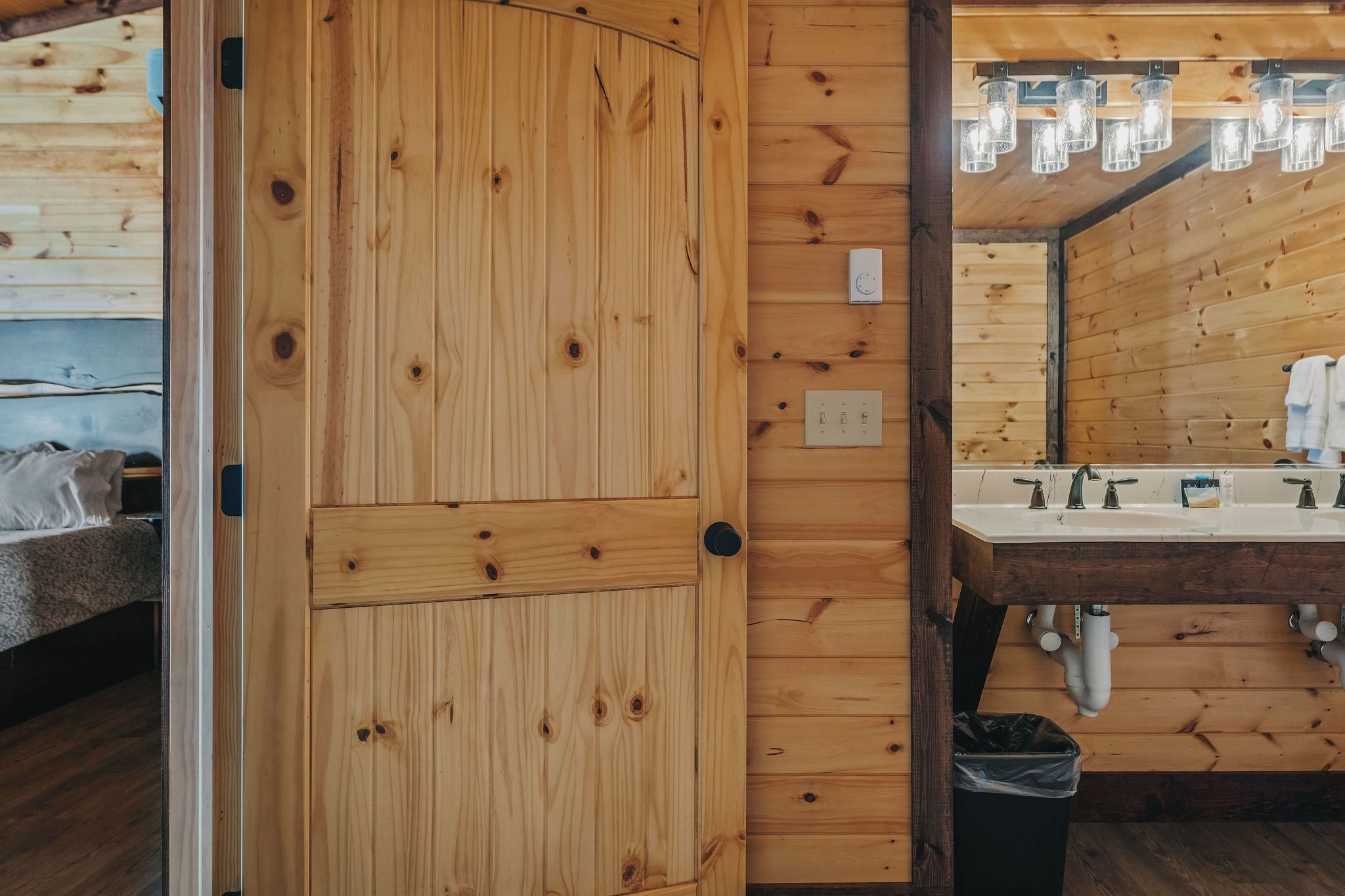 Una puerta de madera con manija, un baño con lavamanos y un espejo.